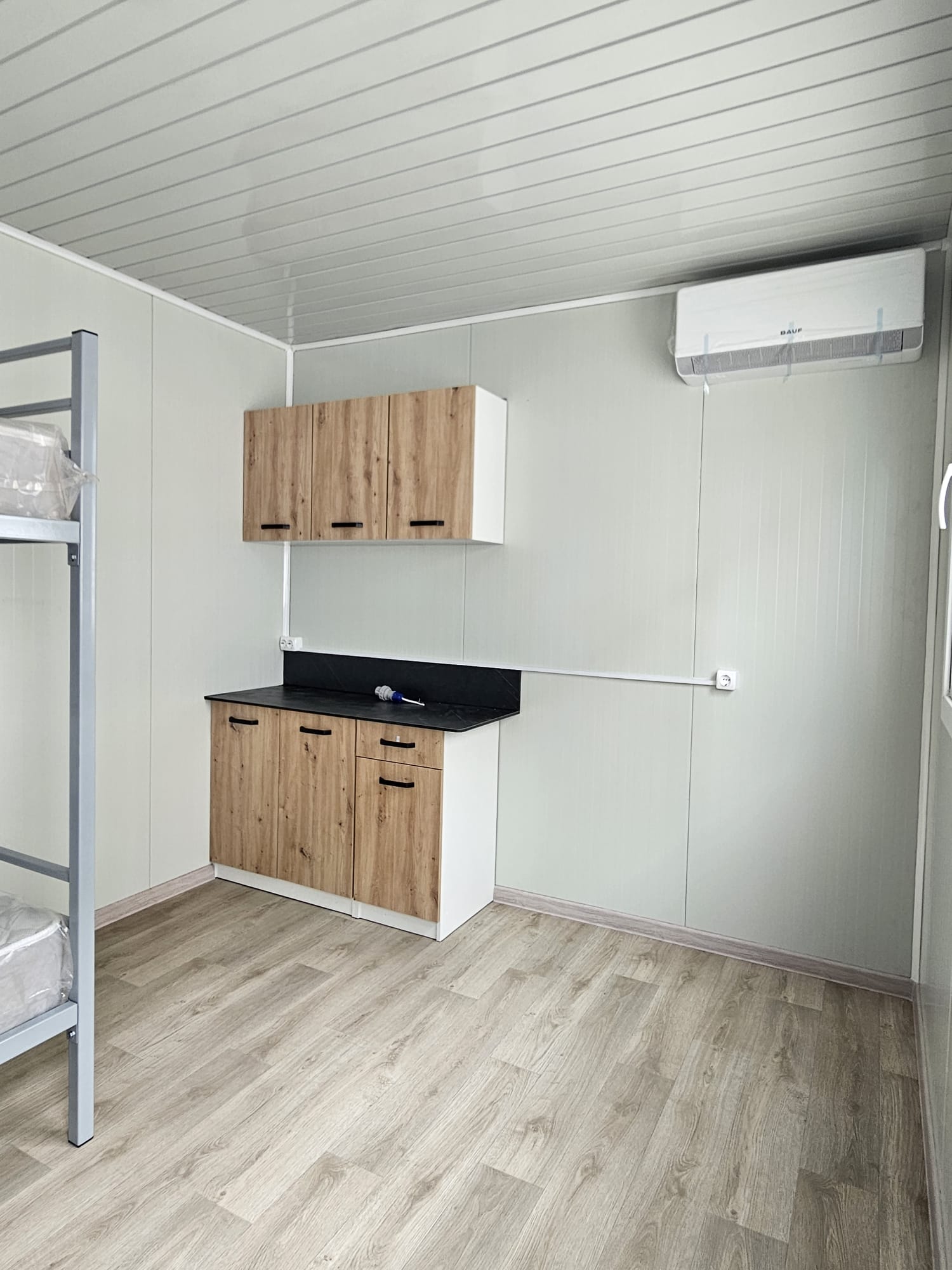 Chicinetă modulară cu mobilier din lemn, blat negru și aer condiționat